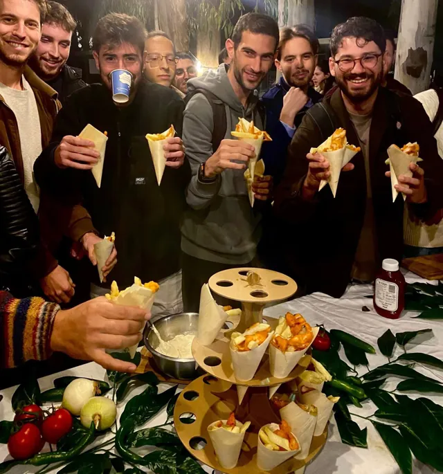 אורחים מחייכים מחזיקים קונוסים של צ'יפס בעמדת דוכן מיוחד